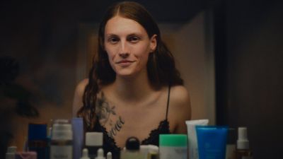 a woman sitting in front of a mirror with lots of skin care products