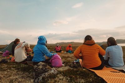 a group of people sitting on top of a grass covered field