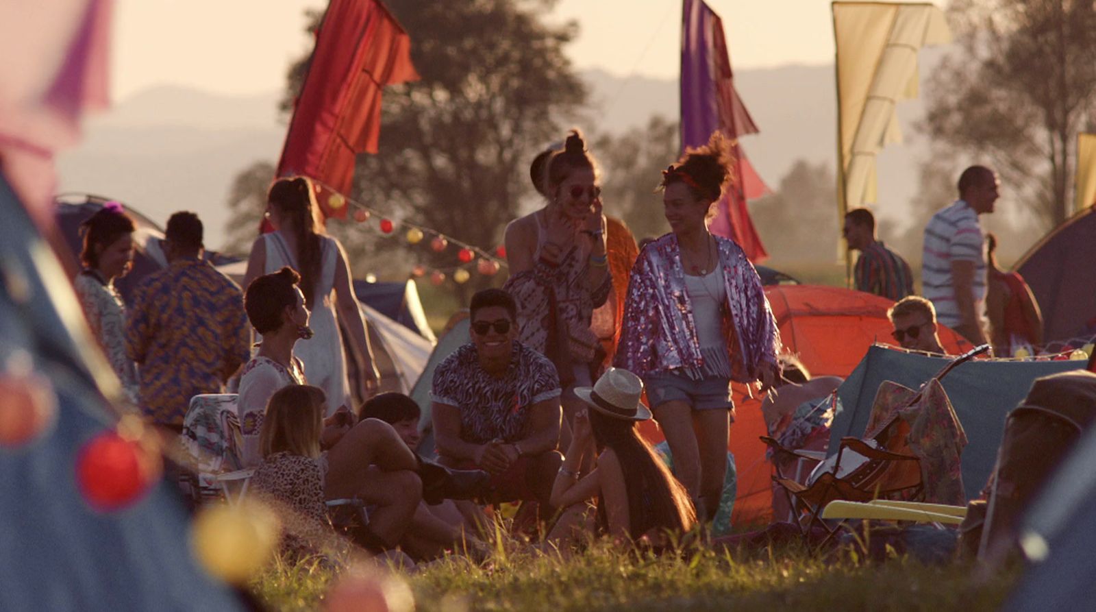 a group of people sitting in a field next to tents