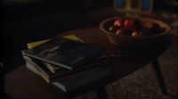 a wooden table topped with books and a basket of apples