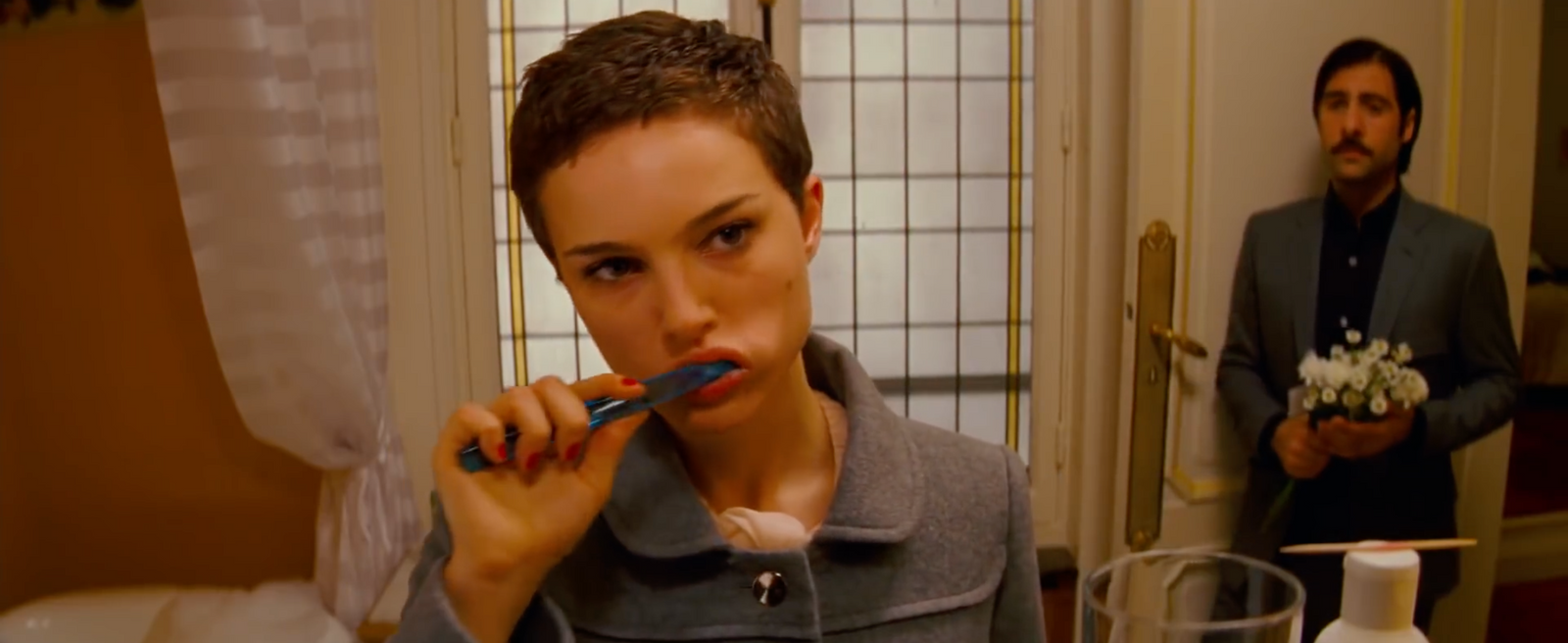 a woman brushing her teeth in front of a man