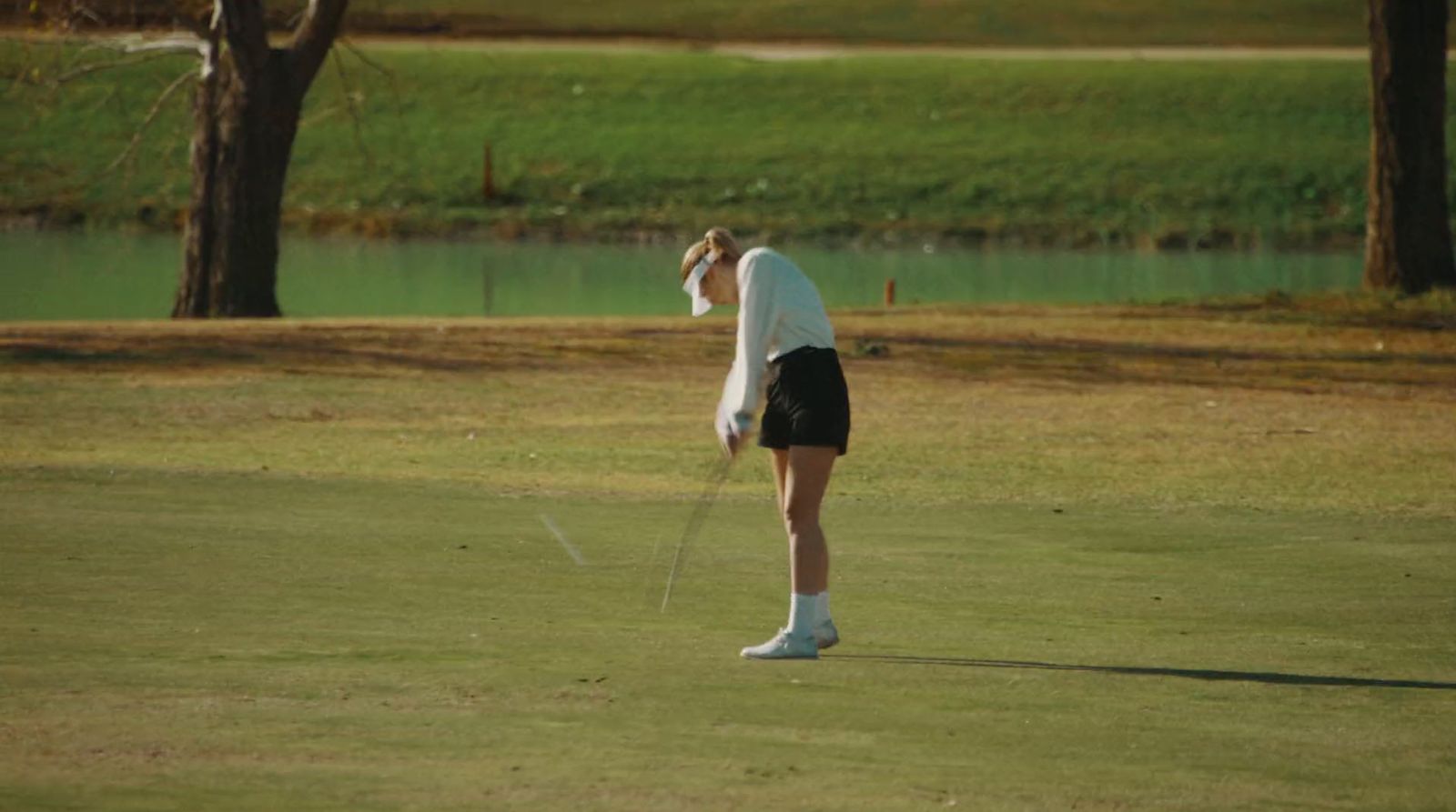 a woman standing on top of a green golf field