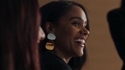 a woman smiling and wearing a pair of earrings