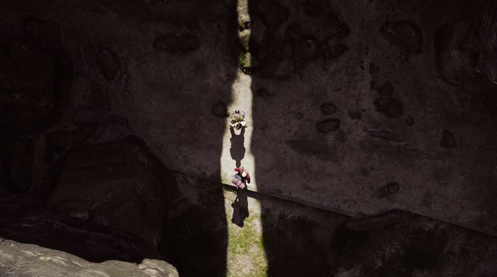 two people standing in a cave looking down at the ground