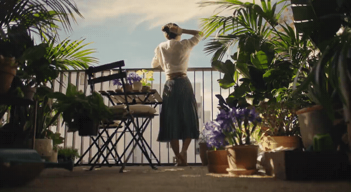 a woman standing on a balcony next to potted plants