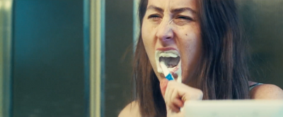 a woman brushing her teeth in front of a mirror