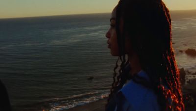 a woman standing on top of a beach next to the ocean