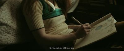 a woman sitting on a couch writing on a piece of paper