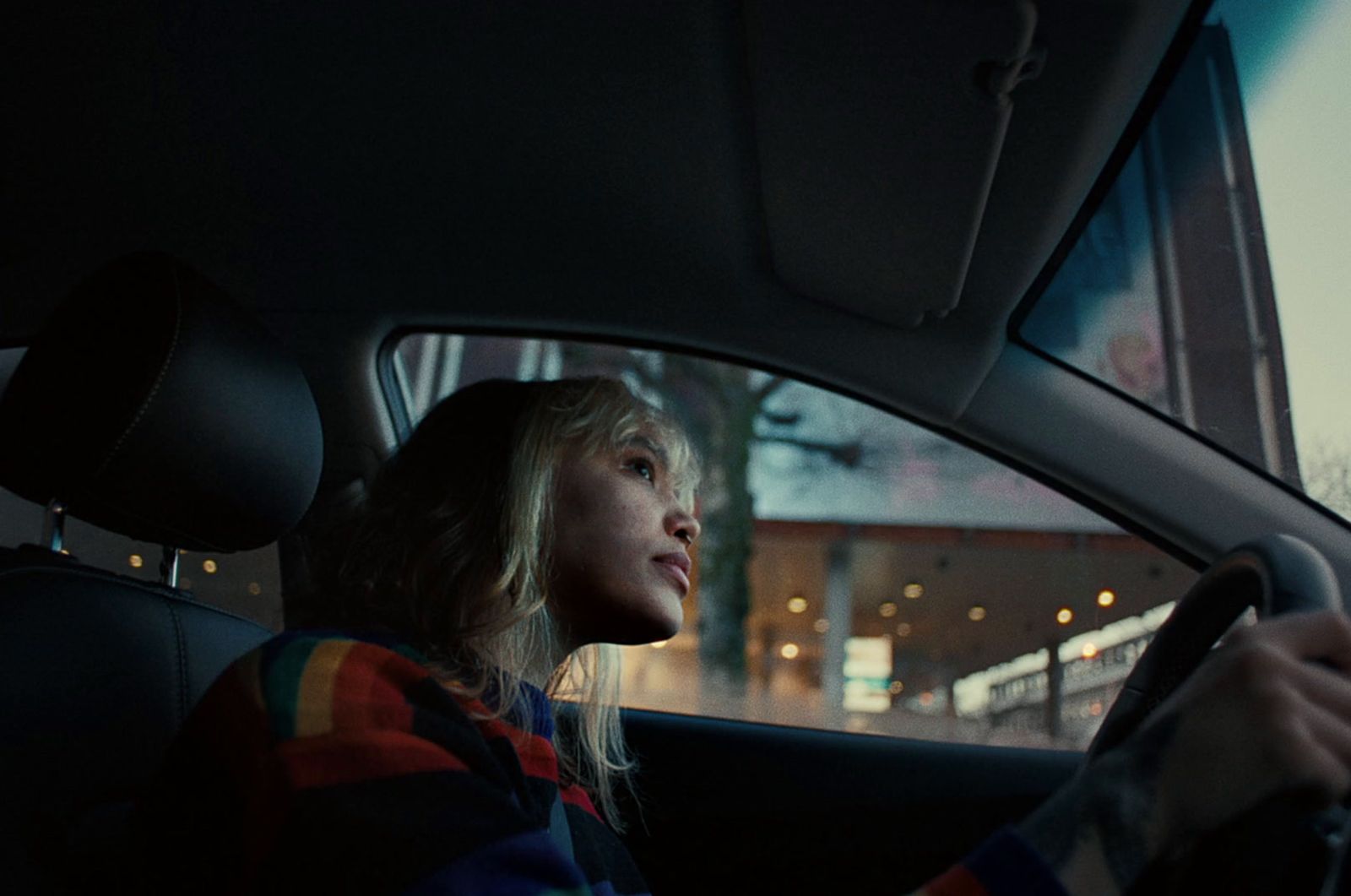 a woman sitting in a car with a steering wheel