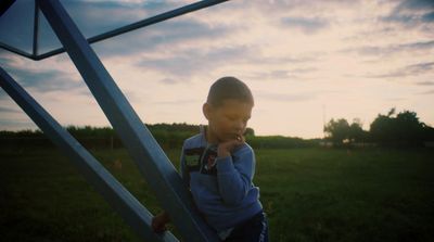 a young boy standing next to a metal structure