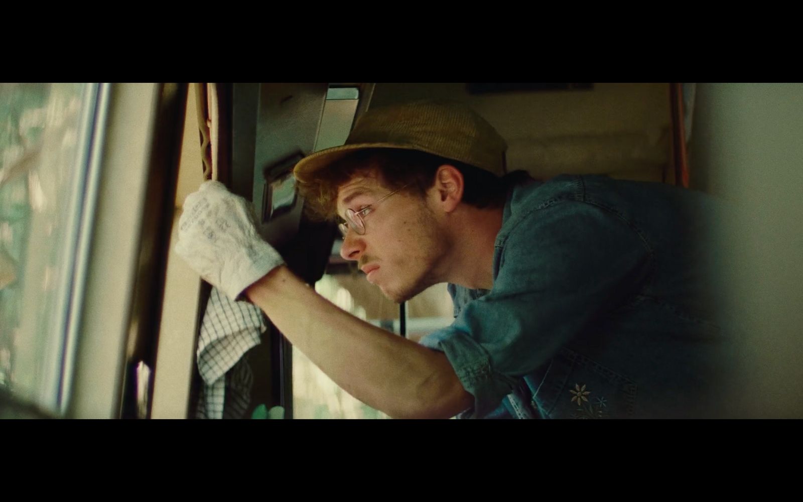 a man with a hat and gloves on leaning against a window