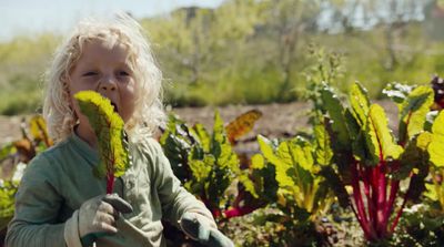 a little girl standing in a garden holding a plant