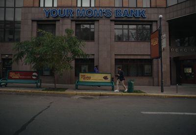 a couple of people walking past a bank