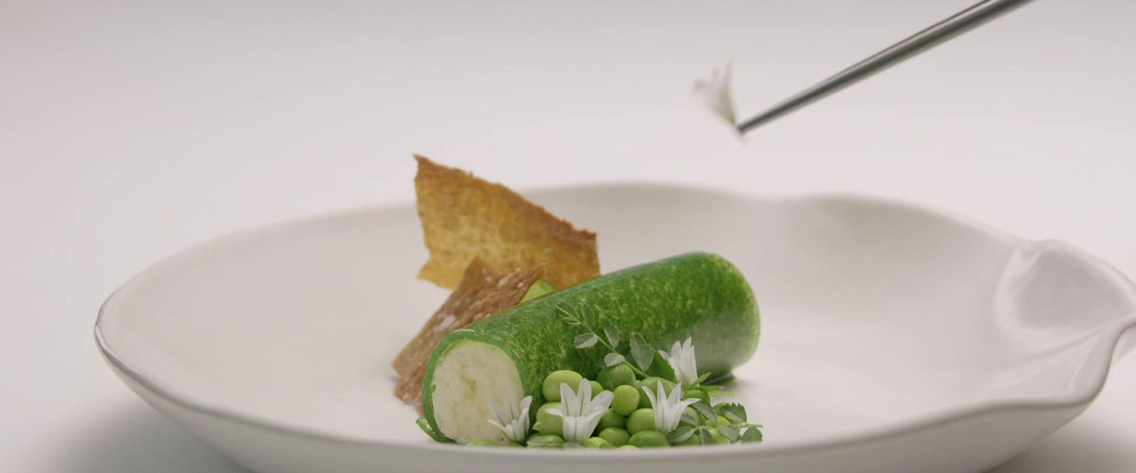 a white bowl filled with a cucumber and a slice of bread