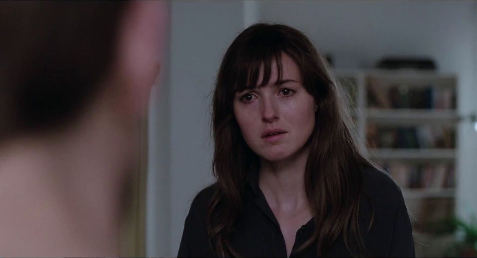 a woman standing in front of a man in a living room