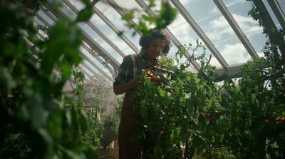 a man standing in a greenhouse holding a plant