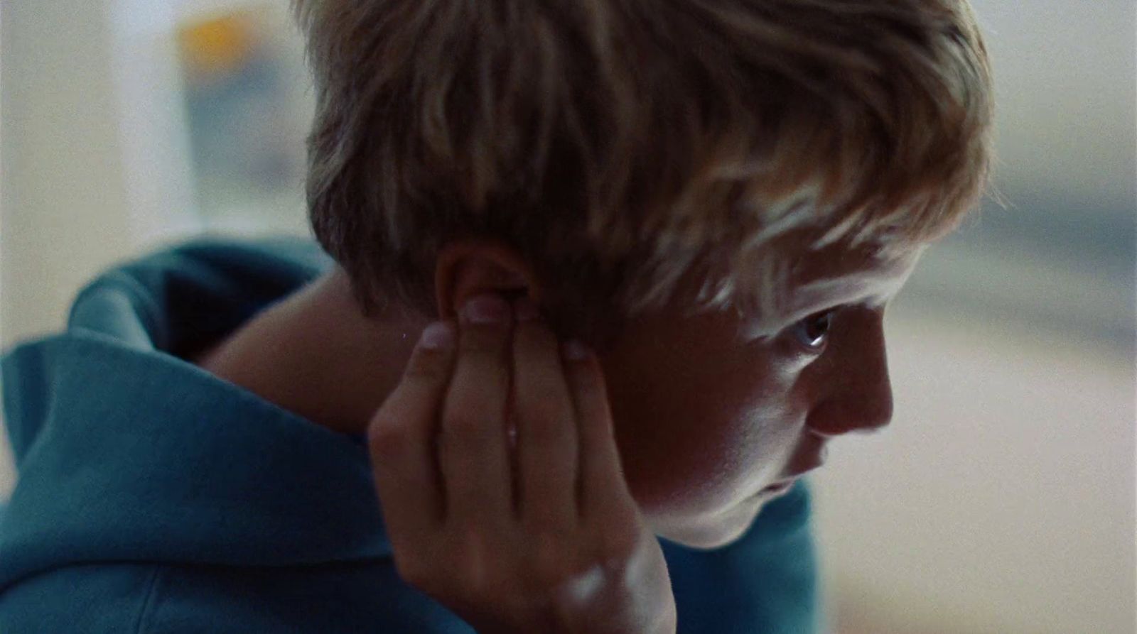 a young boy holding his ear to his ear