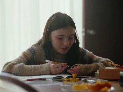 a woman sitting at a table with a pen in her hand