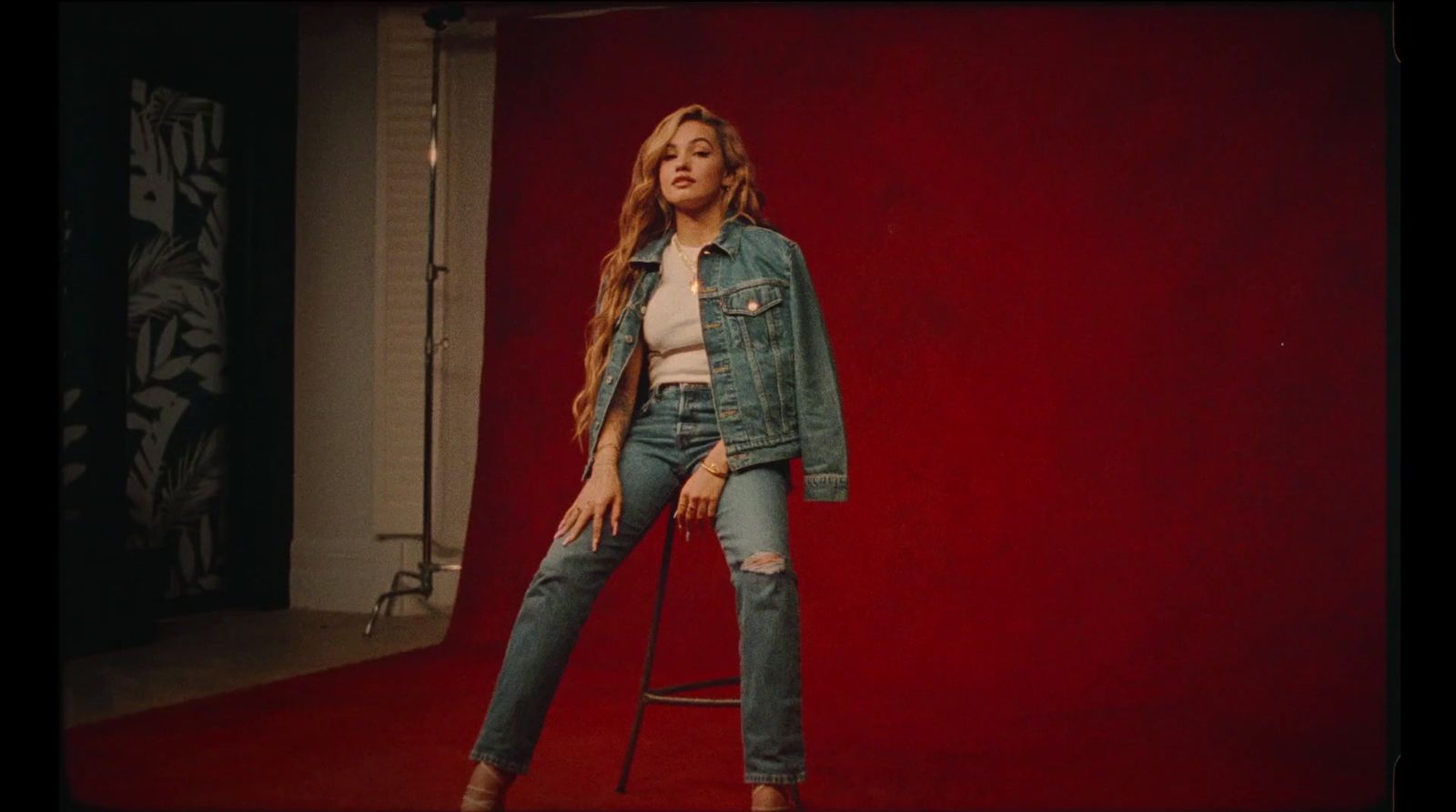 a woman standing on a stool in front of a red wall