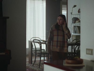 a woman standing in a living room talking on a cell phone