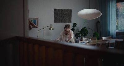 a woman sitting at a table in front of a lamp