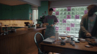 a man standing in a kitchen next to a table