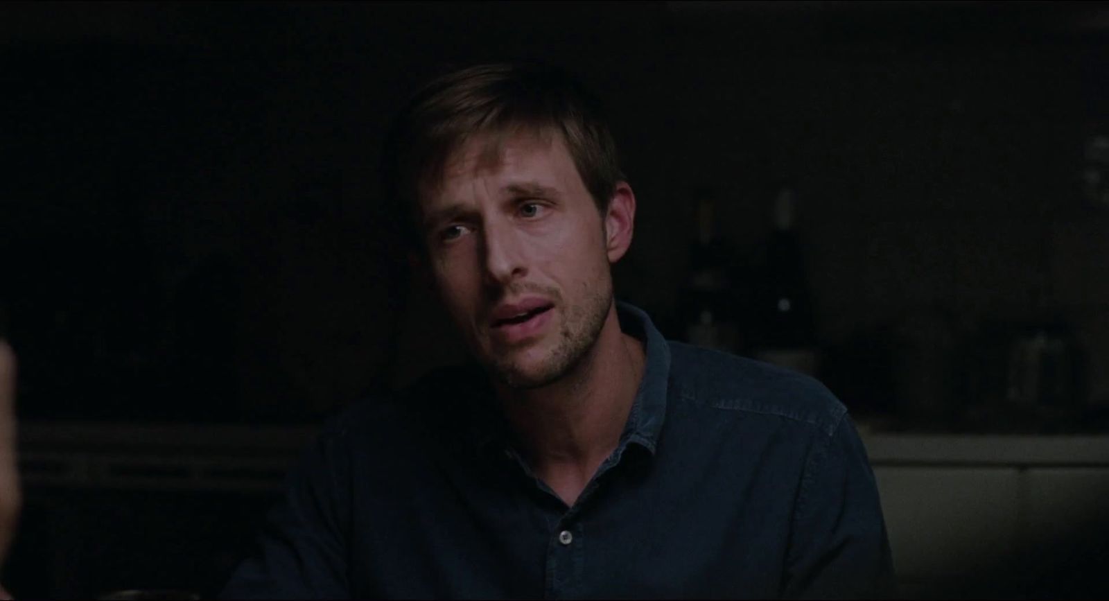 a man in a dark room looking at the camera