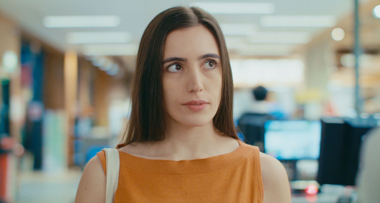 a woman in an orange top looking at the camera