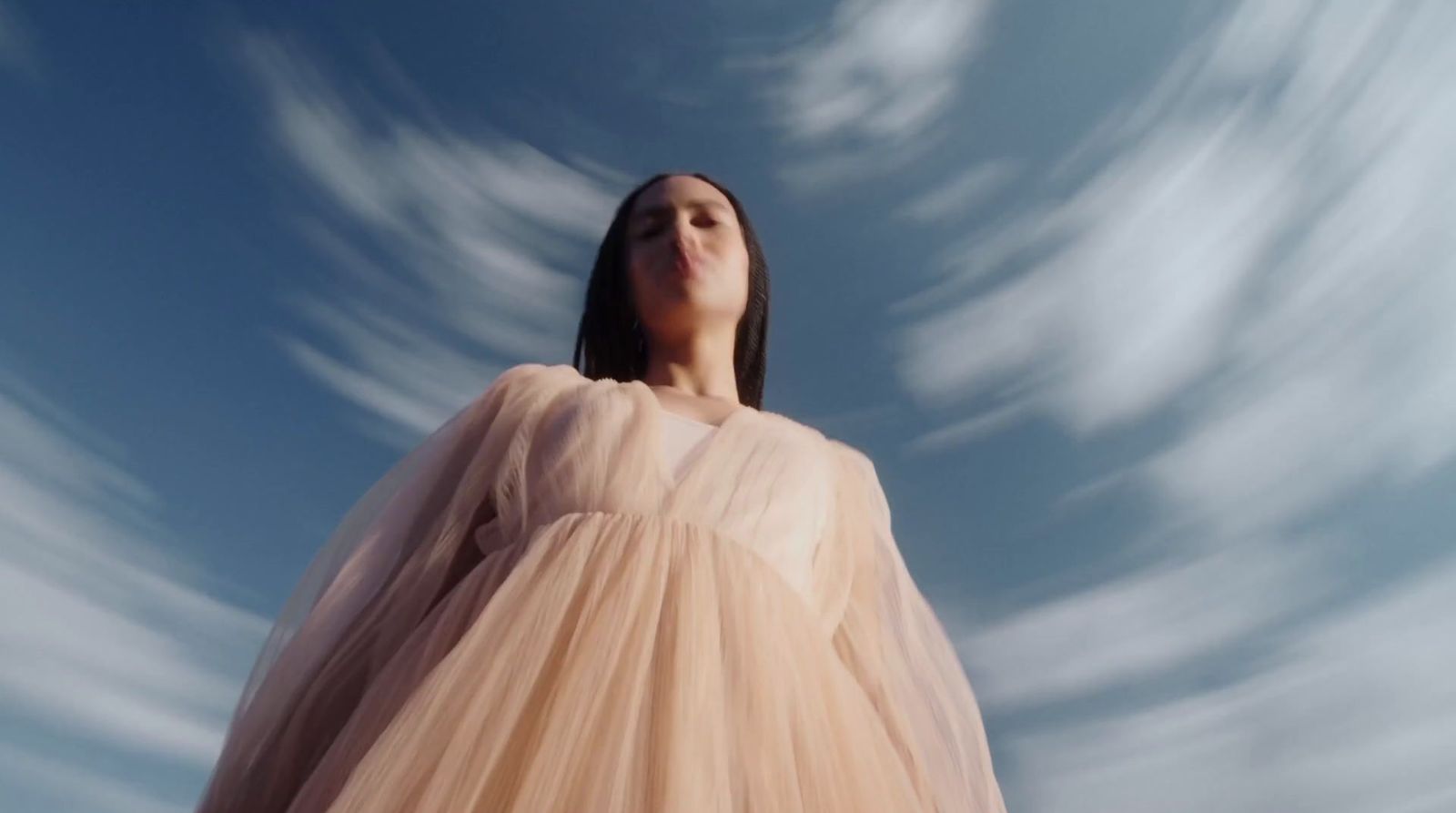 a woman in a dress looking up into the sky