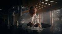 a man in a chef's coat preparing food on a plate