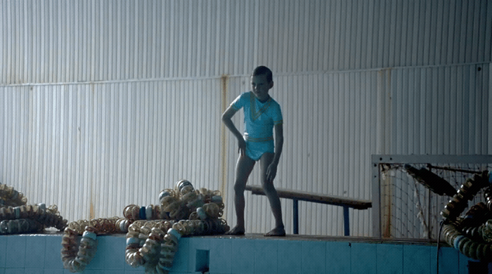 a statue of a boy standing on top of a swimming pool
