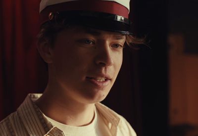 a young man wearing a sailor's hat in a dimly lit room