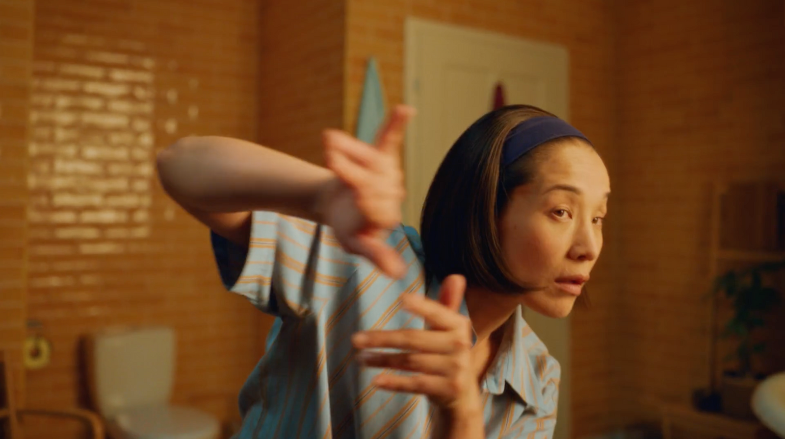 a woman in a blue and white shirt is holding a toothbrush