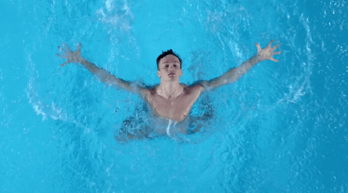 a man swimming in a pool with his arms outstretched