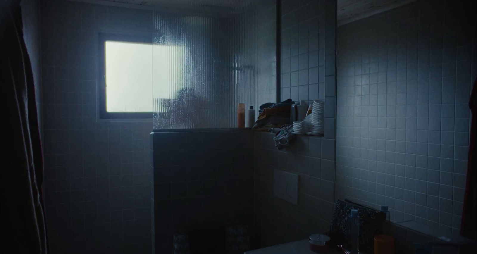 a dark bathroom with a window and a sink