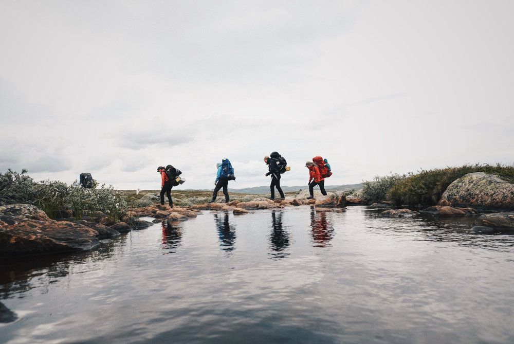 a group of people standing on top of a rock next to a body of water