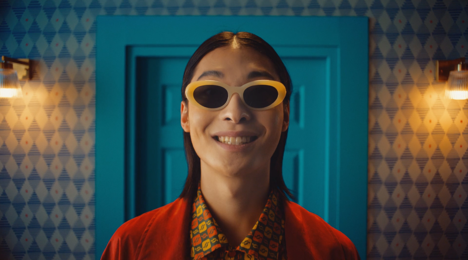 a woman wearing yellow sunglasses standing in front of a blue door