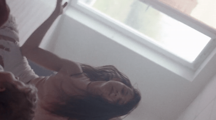 a woman standing in front of a window with her arms in the air