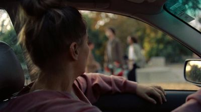 a woman sitting in a car with a man standing behind her