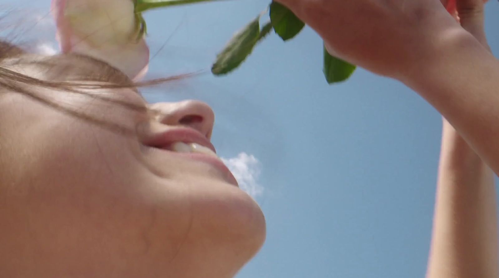 a woman holding a rose up to her face