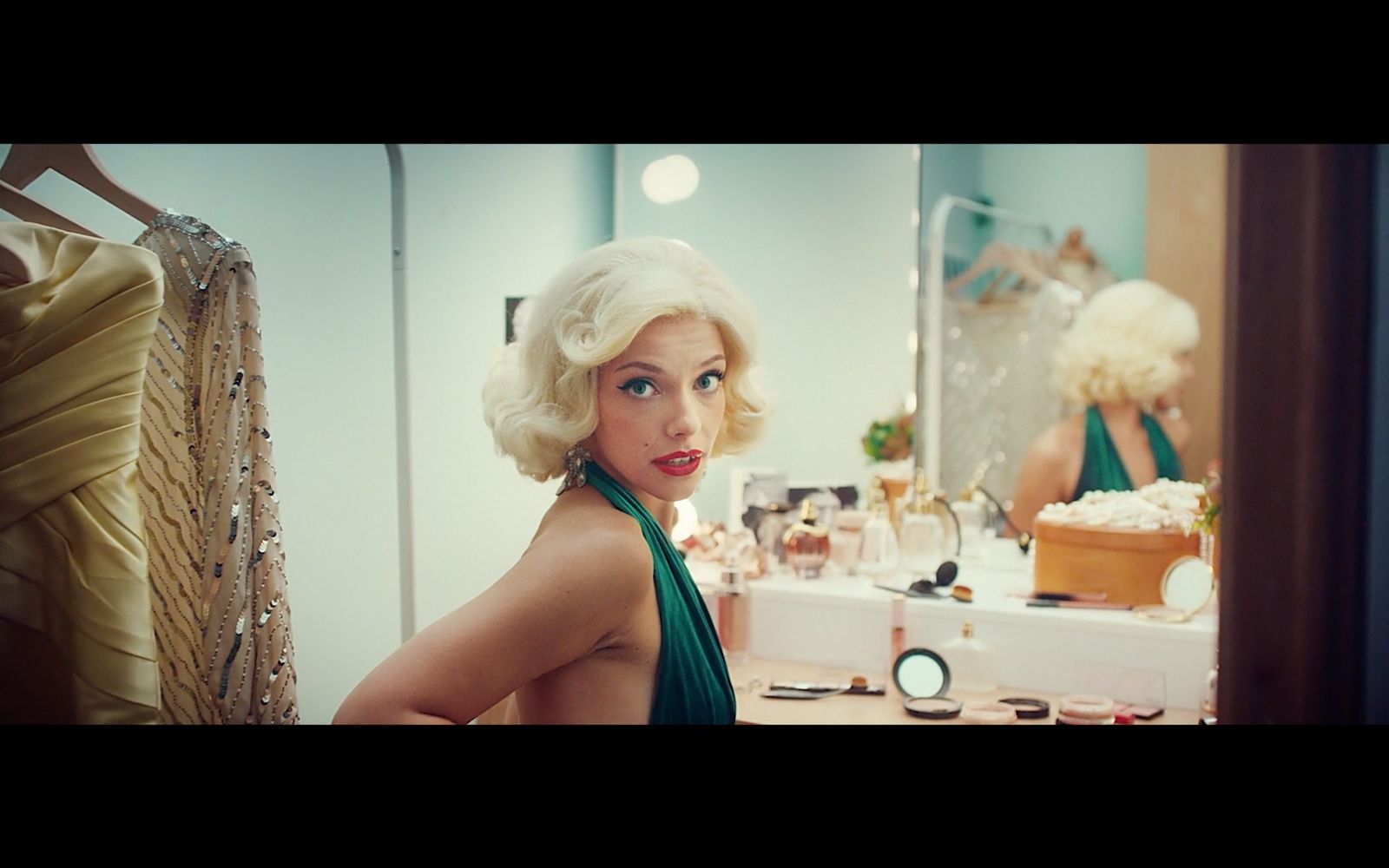 a woman in a green dress standing in front of a mirror