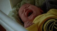 a baby crying in a crib with a blanket