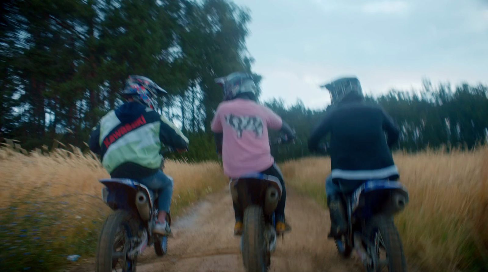 a couple of people riding bikes down a dirt road