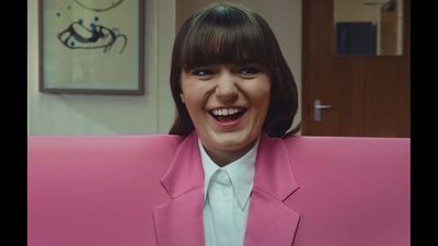 a woman sitting on a pink couch with a smile on her face