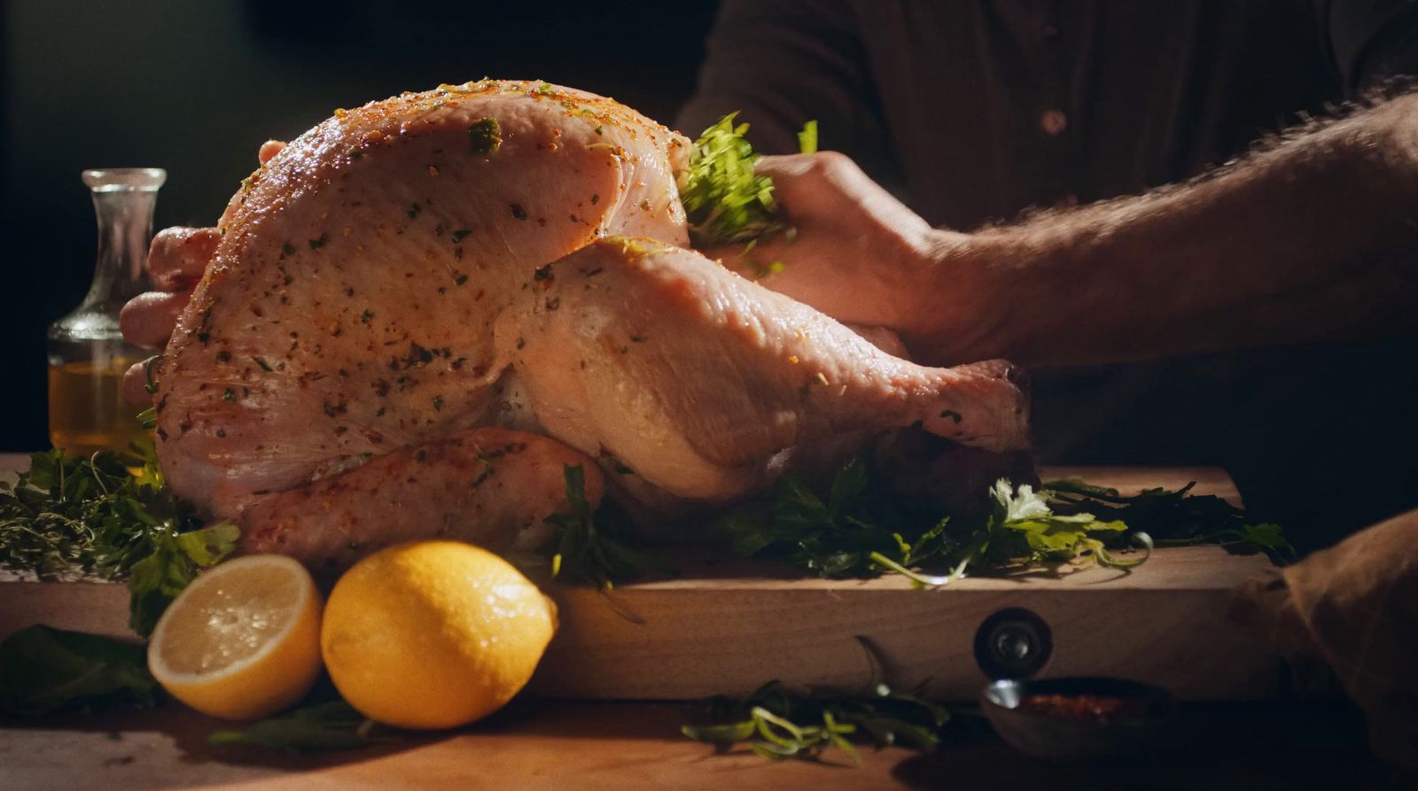 a person holding a whole turkey on a cutting board