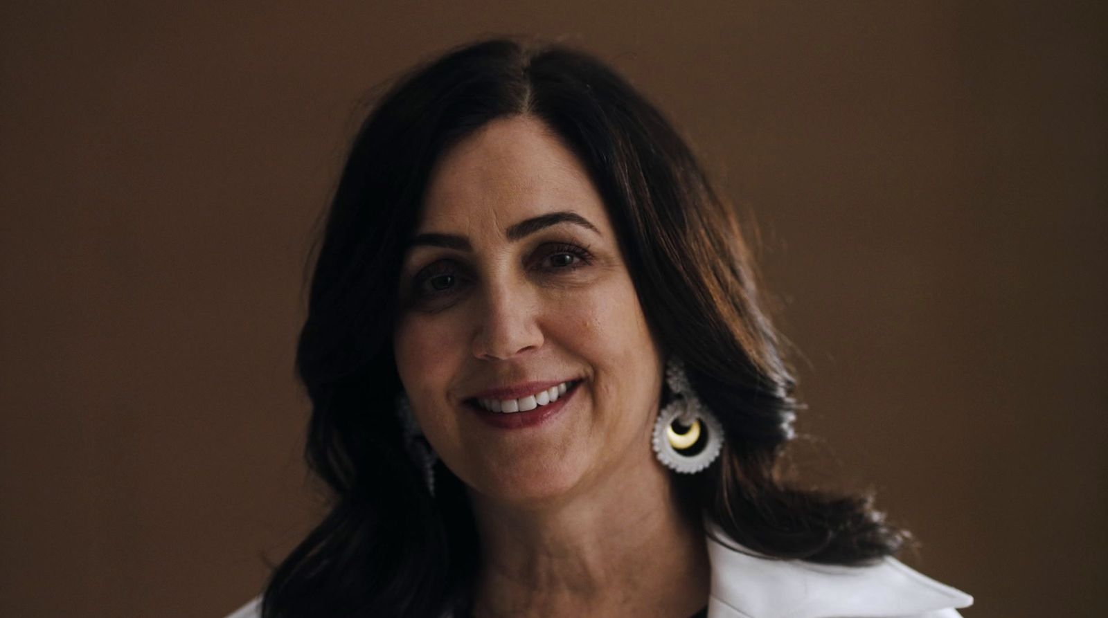 a woman in a white shirt smiles at the camera