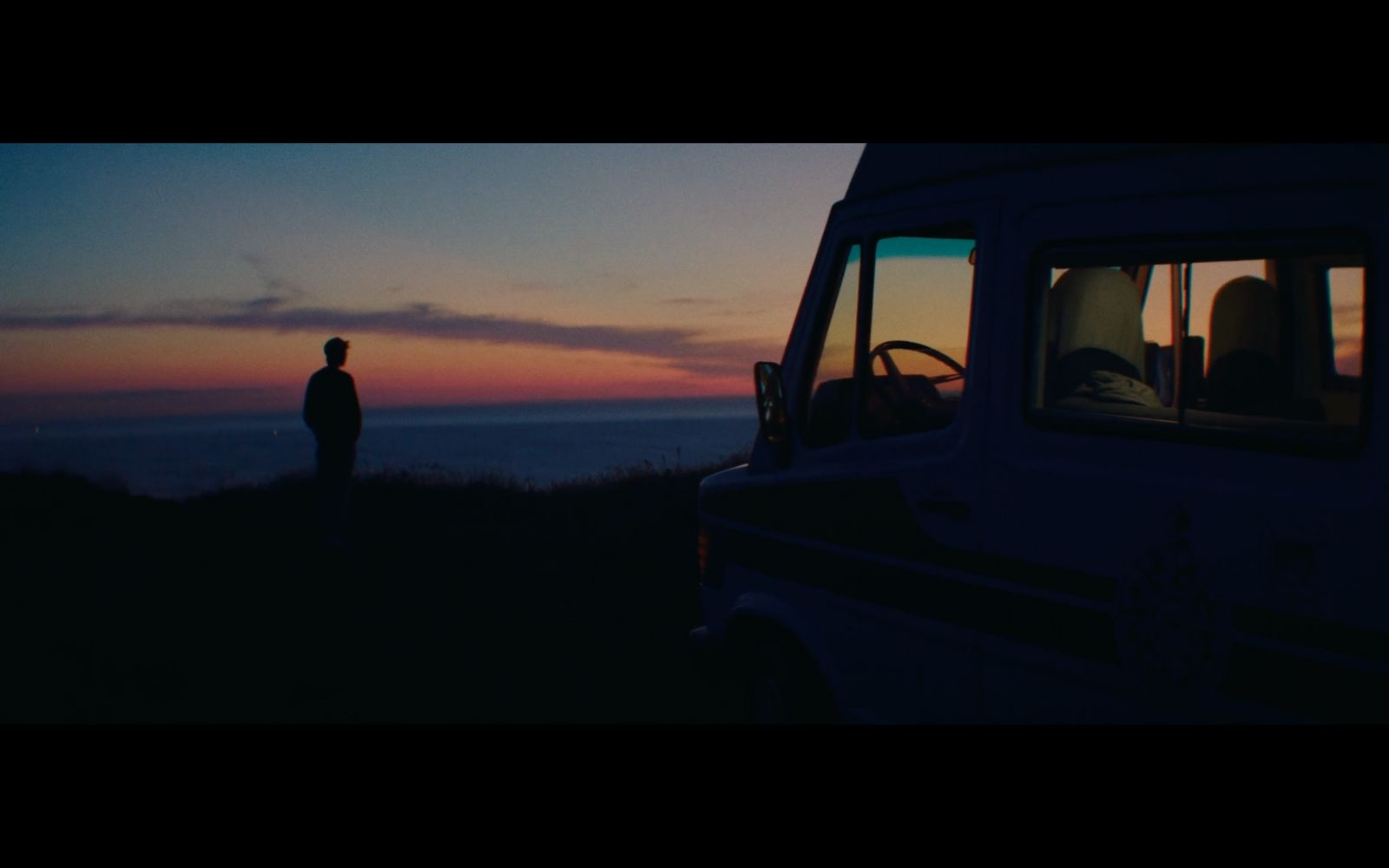 a man standing next to a van at sunset