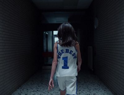 a girl in a basketball uniform walking down a hallway