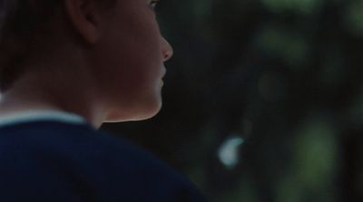 a young boy in a blue shirt looking away from the camera