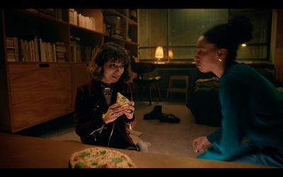 two women sitting at a table eating pizza